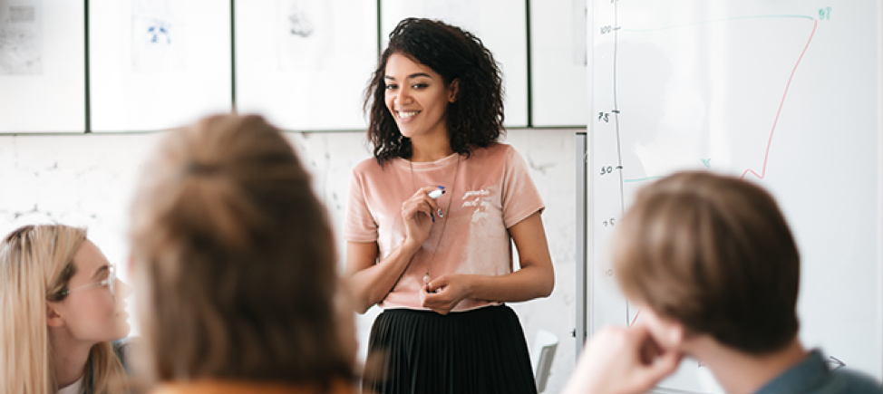 new ideas A young woman stands in front of a whiteboard during a meeting.